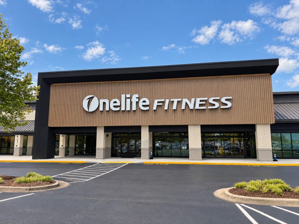 OneLife Fitness gym exterior with a parking lot and blue sky.
